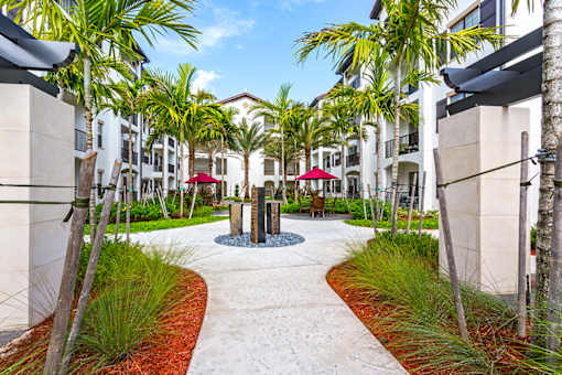 A walkway with a red umbrella in the middle of it.