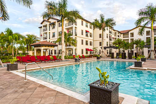 A pool area with a red chair and a building in the background.