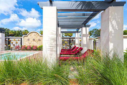 A white building with a pool and red chairs.