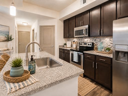 A kitchen with a sink, stove, and refrigerator.