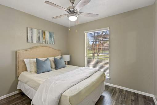 A bedroom with a large bed and a ceiling fan.