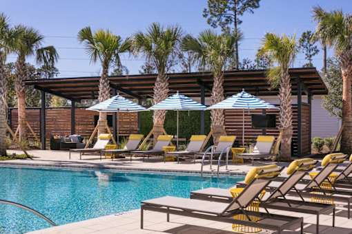 A pool area with sun loungers and umbrellas.