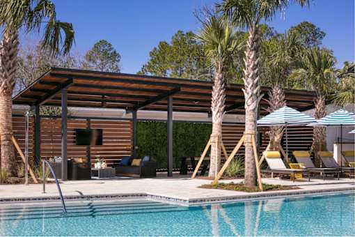 A pool area with a wooden building and palm trees.