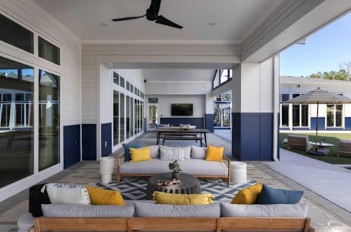 A modern outdoor living space with a wooden sofa and yellow pillows.