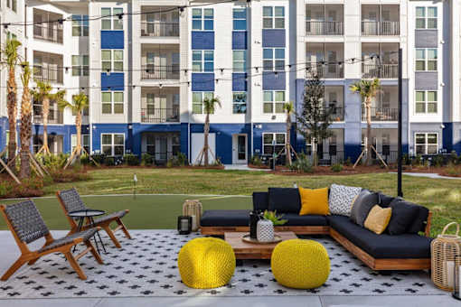 A patio with a black and white checkered floor and a yellow ottoman.