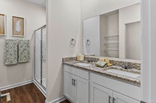 A bathroom with a sink, mirror, and shower.
