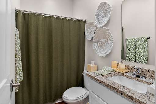 A bathroom with a green shower curtain and a white toilet.