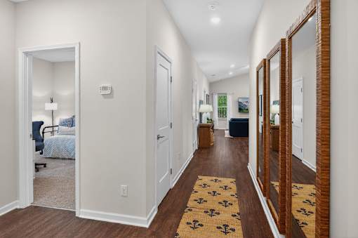 A hallway with a rug on the floor and a mirror on the wall.