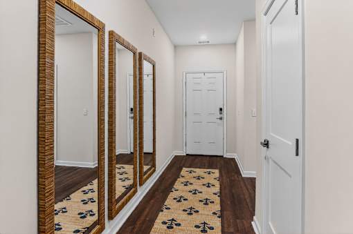 A hallway with a rug and mirrors on the wall.
