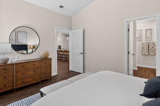 A bedroom with a large bed, a dresser, and a mirror.