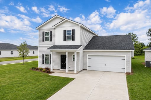 A two-story house with a garage is surrounded by a well-kept lawn.