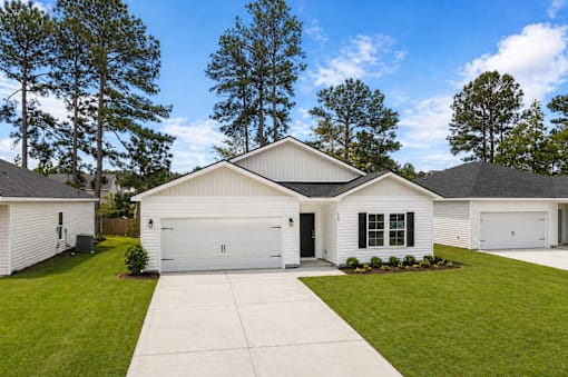 A white house with a black roof and a garage door.