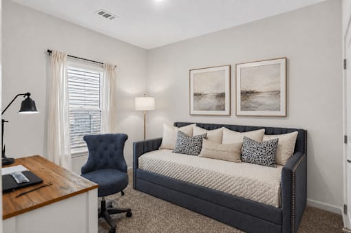 A bedroom with a bed, chair, and two pictures on the wall.