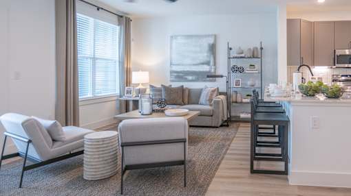 A modern living room with a grey sofa, a white armchair, and a coffee table.