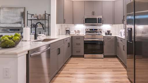 A modern kitchen with stainless steel appliances and wooden floors.