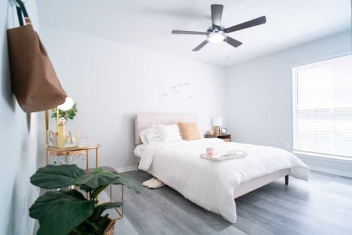 a white bedroom with a bed and a ceiling fan