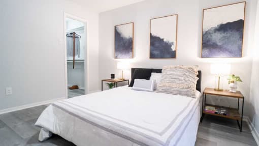 a bedroom with a white bed and paintings on the wall
