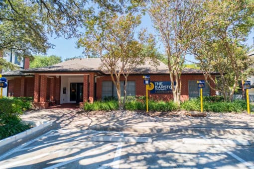 a brick building with a sign and trees in front of it
