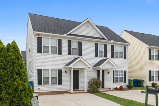 a white house with black shutters and a driveway