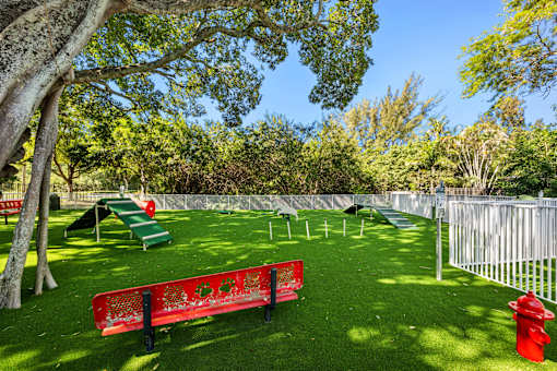 A playground with a red bench and a red fire hydrant.