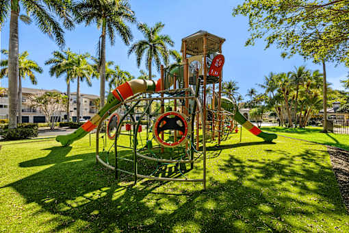 A playground with a green slide and a red and white striped barrier.
