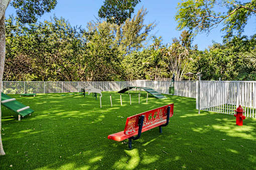 A red bench sits in a green park.