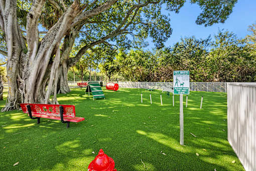 A park with a red fire hydrant on the grass.