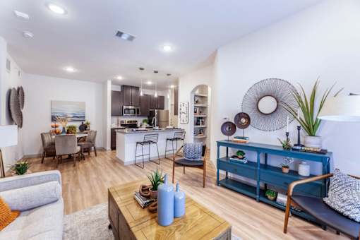 A modern living room with a kitchen in the background.