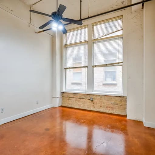 A room with a ceiling fan and a window with blinds.