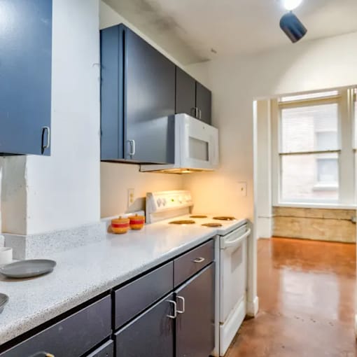 A kitchen with a white microwave above a stove and a white dishwasher.