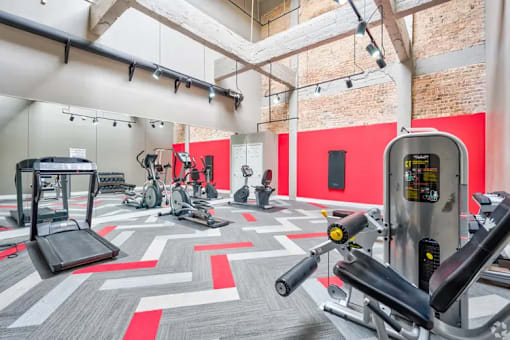 A gym with a variety of exercise equipment including treadmills, stationary bikes, and weight machines.