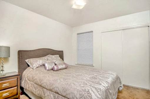 A bedroom with a bed, nightstand, and lamp.