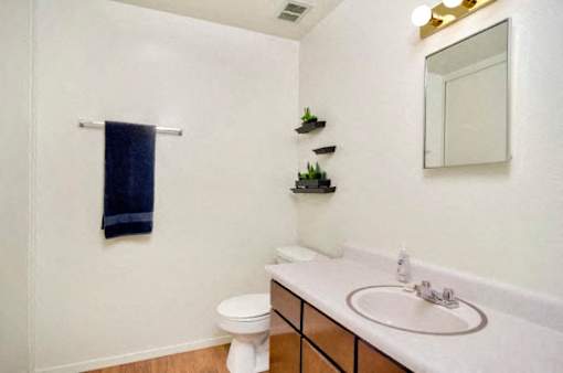 A white bathroom with a toilet, sink, and mirror.