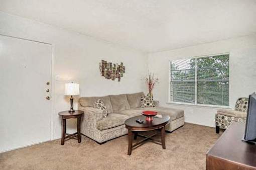 A living room with a couch, a table, and a lamp.