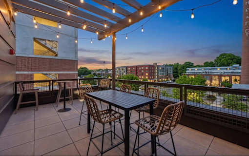 A patio with a table and chairs overlooking a cityscape at dusk.