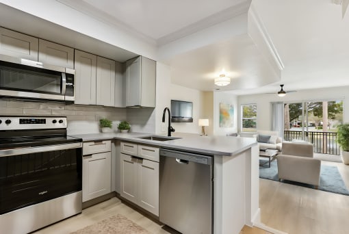 an open kitchen and living room with white cabinets and stainless steel appliances