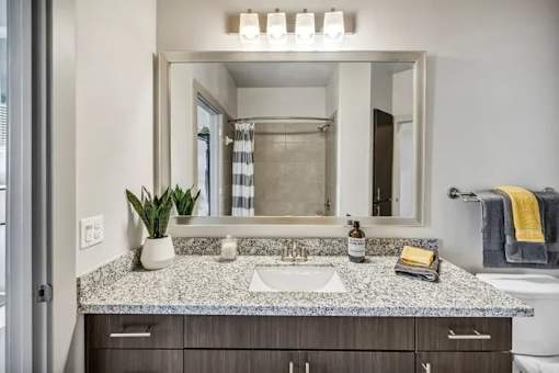A bathroom with a granite countertop and a large mirror above the sink.
