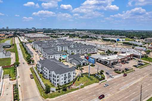 A large apartment complex is surrounded by a parking lot and a road.