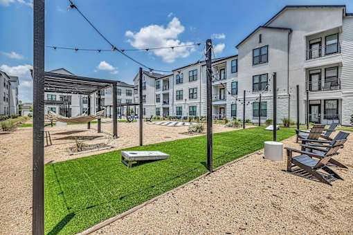 A sunny day at a modern apartment complex with a playground and lawn chairs.