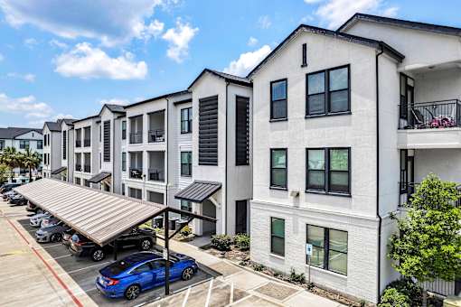 A row of modern townhouses with a blue car parked in front.