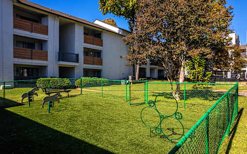 A green fence surrounds a small grassy area with a playground.