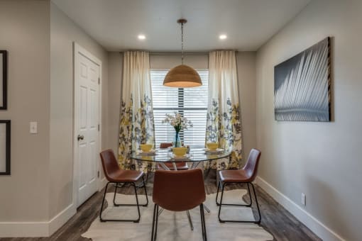 a dining room with a table and chairs in front of a window