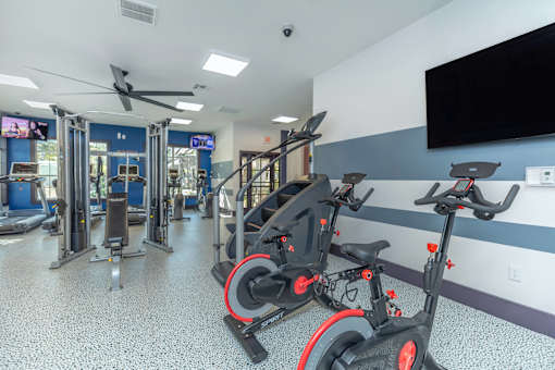 A gym with exercise equipment and a television on the wall.