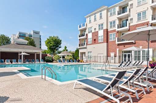 A pool with sun loungers and a building in the background.