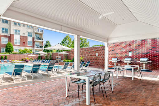 A patio with a table and chairs overlooking a pool.