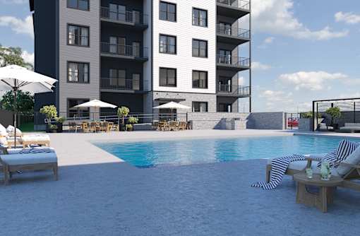 A modern apartment complex with a pool and lounge chairs.