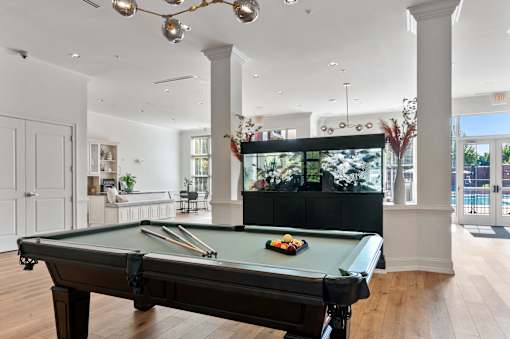 A pool table in a room with a fish tank in the background.