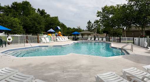A large swimming pool surrounded by white lounge chairs and umbrellas.