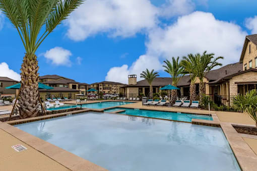 A large swimming pool surrounded by palm trees and lounge chairs.