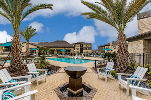 A pool surrounded by palm trees and lounge chairs.